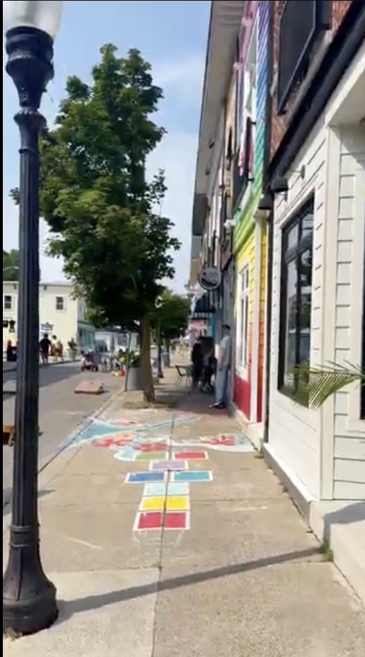 Still from the Fort Erie footage library: the Erie Road and Derby Road strip, a painted hopscotch grid on the sidewalk and rainbow-coloured storefronts down the block.
