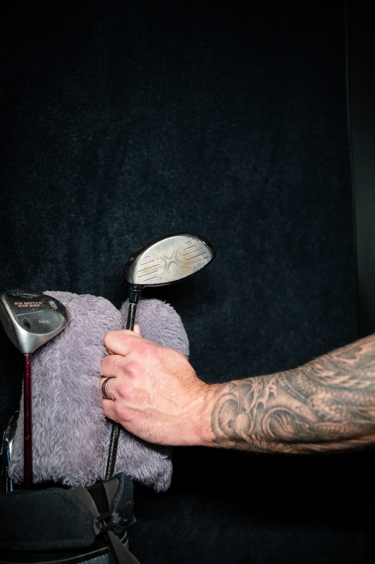 Detail shot of a golfer pulling a driver from a golf bag.